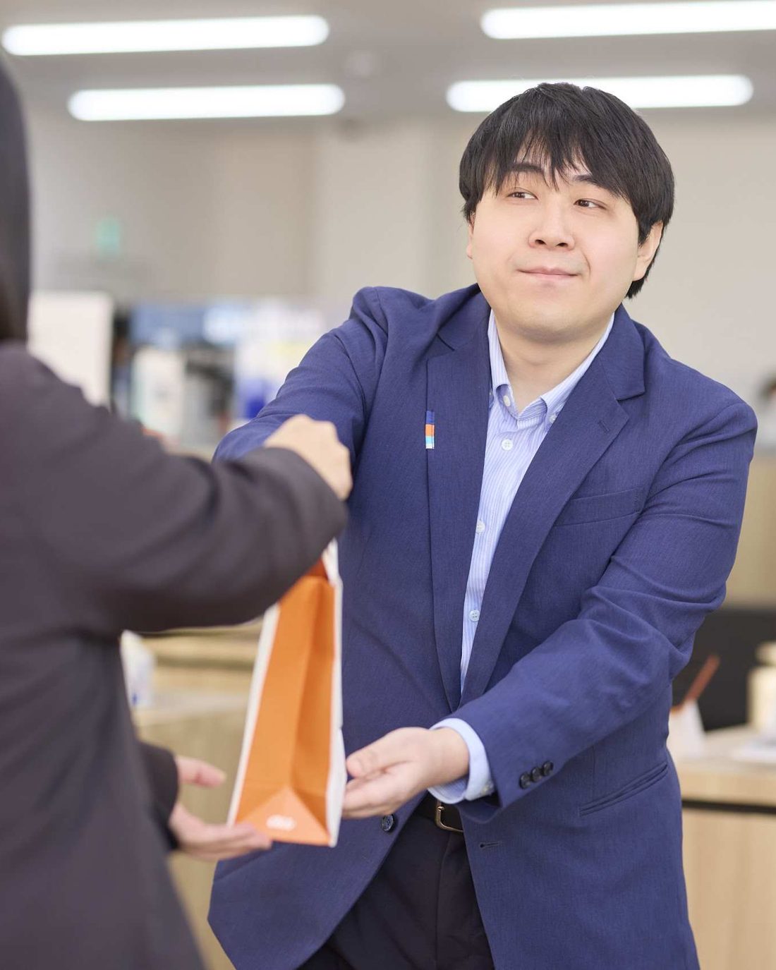 商品の入った袋をお客様に手渡すスタッフ