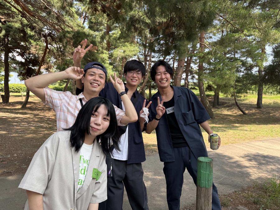 屋外のレクリエーションでポーズをとる社員4人